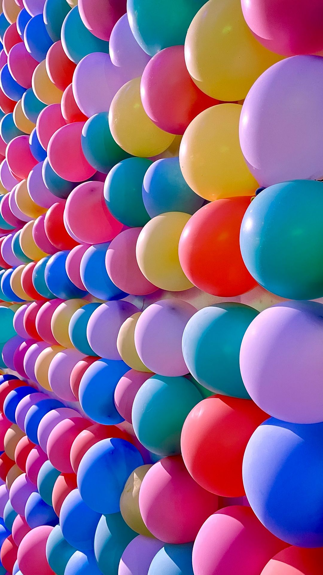 a bunch of balloons are lined up against a wall